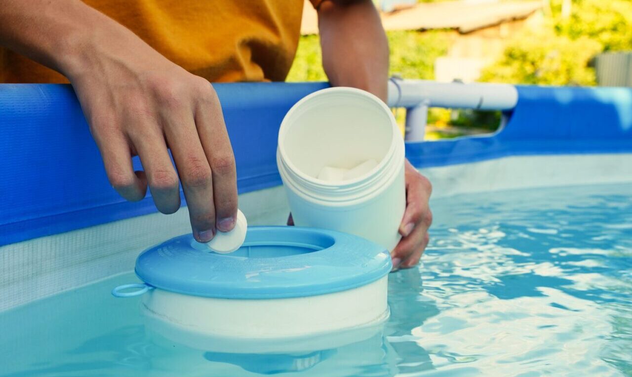 Personne versant de l’eau de Javel dans une piscine depuis un bidon gradué